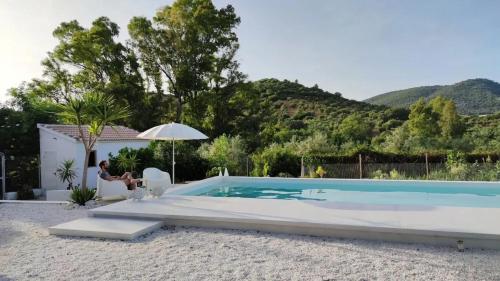 un uomo seduto su una sedia accanto alla piscina di Charming Bungalow in Madrigueras a Madrigueras