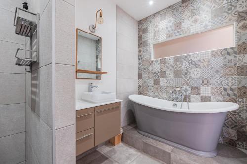 une salle de bain avec une baignoire et un lavabo dans l'établissement L'Écrin Strasbourgeois - T3 avec grande terrasse, à Strasbourg