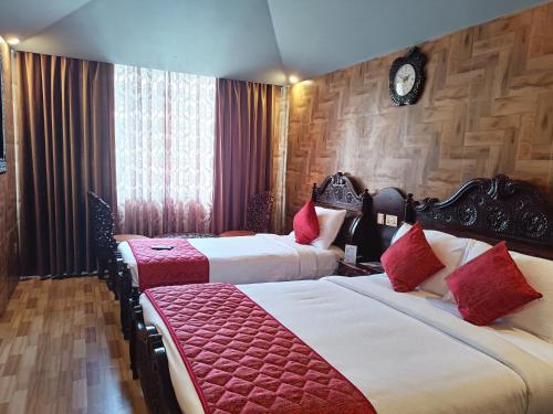 a hotel room with two beds with red pillows at HYDERS PARK- THE LUXURY HOTEL in Kodaikānāl
