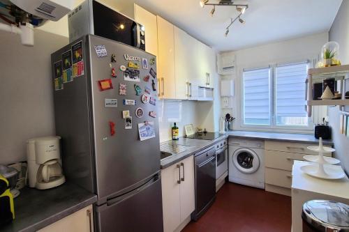 - une cuisine avec un réfrigérateur en acier inoxydable et des aimants dans l'établissement Apartment with balcony near the sea, à Arcachon