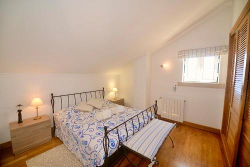a bedroom with a bed with a bench and a window at 'Collasão' - Stunning Duplex with Pool & Sea Views in São Martinho do Porto