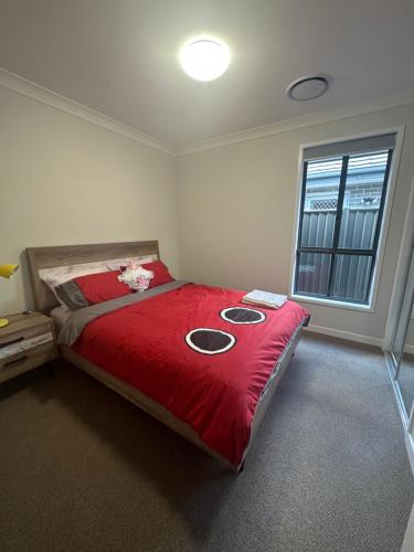 Un dormitorio con una cama con sábanas rojas y una ventana. en 4 Bedrooms Home, en Gledswood Hills