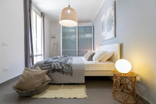 a white bedroom with a bed and a lamp at Marzamemi Terrazza vista mare in Marzamemi