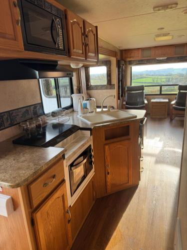an rv kitchen with wooden cabinets and a sink at 5th Wheel Trailer in Bere Alston