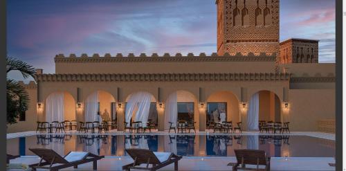 a resort with a pool and chairs and a clock tower at Kenzi Azghor in Ouarzazate