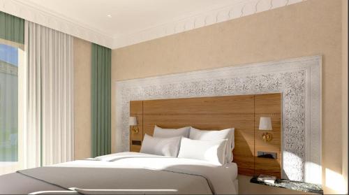 a bedroom with a large bed with a wooden headboard at Kenzi Azghor in Ouarzazate