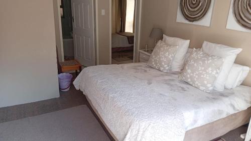 a bedroom with a bed with white sheets and pillows at Walmer Heights Guest House in Port Elizabeth