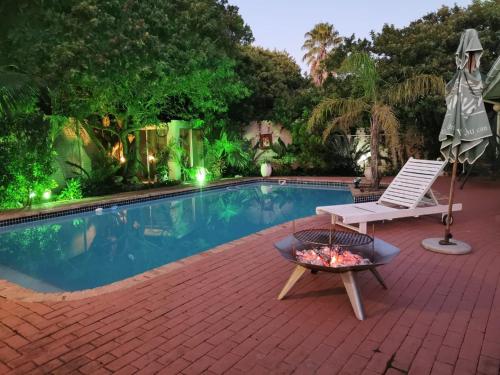 a swimming pool with a white chair and a table and a bench at Walmer Heights Guest House in Port Elizabeth