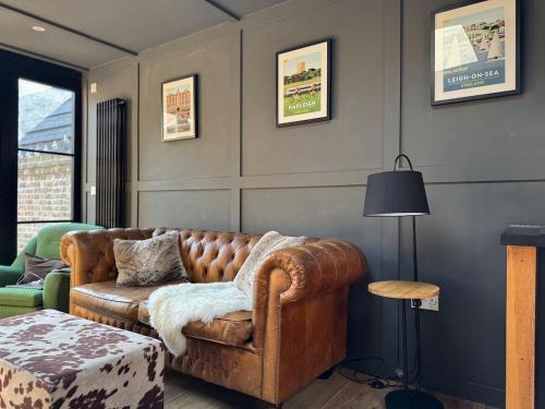 a living room with a brown couch and a table at The Stables in Southend-on-Sea