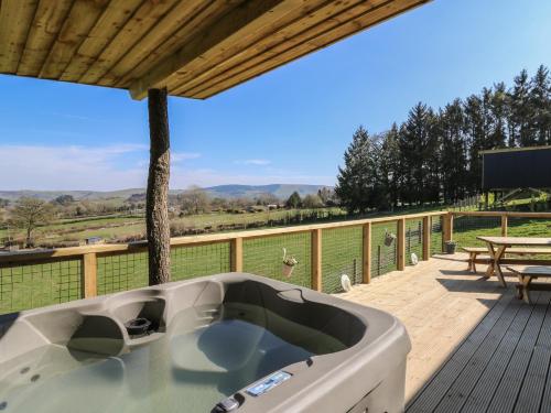 a bath tub on a deck with a table and a picnic table at Llety Cariad in Llandrindod Wells