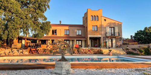 une fontaine en face d'une maison avec un bâtiment dans l'établissement Mas la Marchette, à Oms