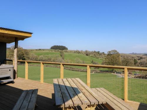 a wooden deck with a bench and a view of a field at Bryn Hafod in Llandrindod Wells