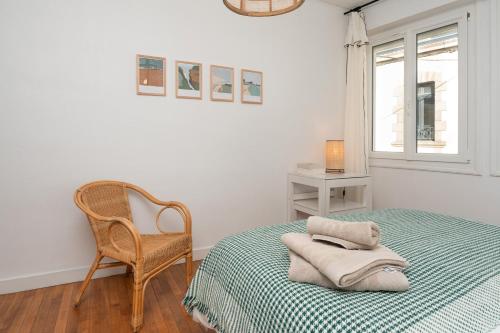 Un dormitorio con una cama y una silla y una ventana. en Maison de vacances, en Groix