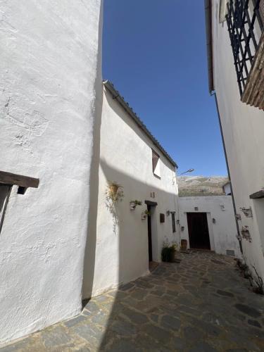 an alley between two white buildings with a doorway at Casa Orencio, bosque encantado de Parauta in Parauta