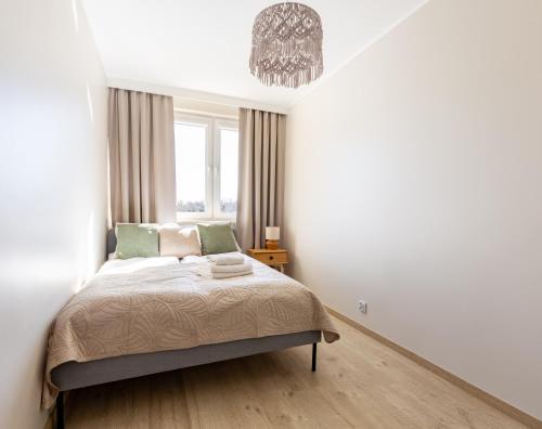 a bedroom with a bed and a chandelier at Wejhera Beige Chic Apartment by BookingHost in Gdańsk