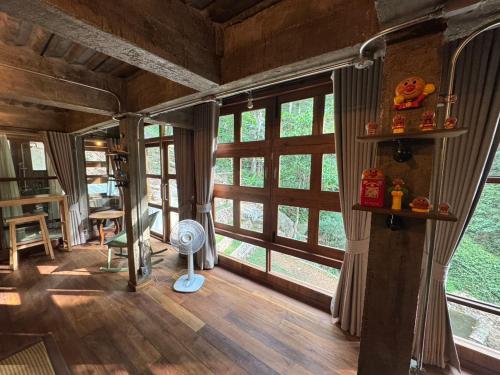 a living room with a large window and a fan at Mii Paa Aii มิ๊ ป๊ะ ไอ in Chiang Mai