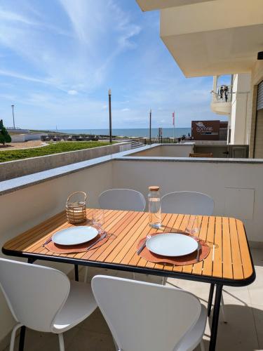 a wooden table and chairs on a balcony with a view of the ocean at Porta da Praia - Paredes da Vitória in Senhora da Vitória