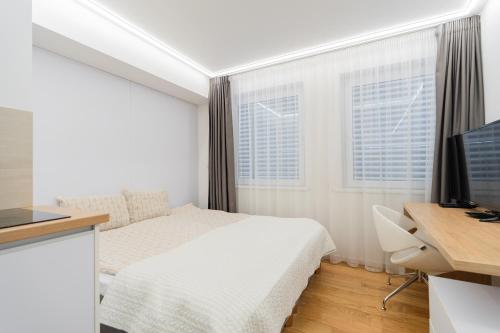 a bedroom with a bed and a desk with a computer at Gynėjų Self Check-in Apartments - Lollo Stay in Vilnius