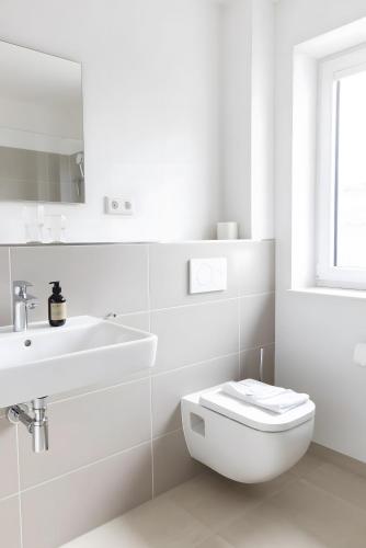 a white bathroom with a toilet and a sink at Backbord in Sankt Peter-Ording