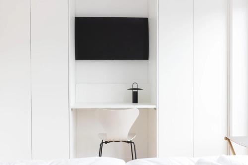 a white room with a chair and a tv at Backbord in Sankt Peter-Ording