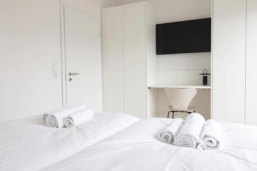 a white bedroom with two beds with towels at Kajüte in Sankt Peter-Ording