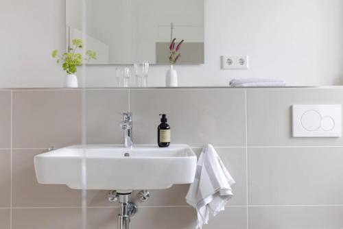 a white bathroom sink with a bottle of wine on it at Kajüte in Sankt Peter-Ording