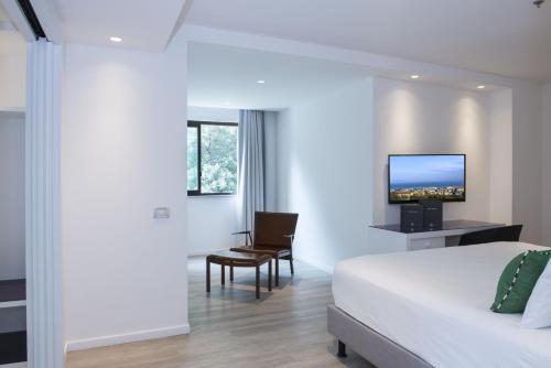 a hotel room with a bed and a chair and a tv at Hilton Sorrento Palace in Sorrento