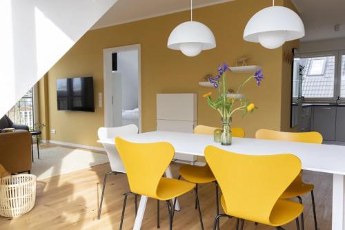 a dining room with a white table and yellow chairs at Strand in Sankt Peter-Ording