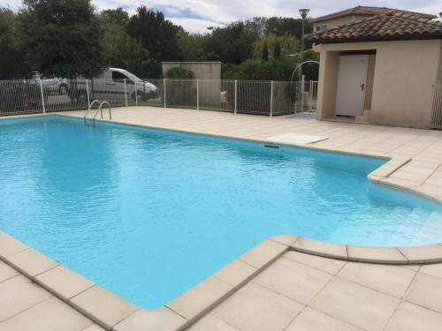 une grande piscine bleue dans une cour dans l'établissement Villa tout confort, à 5mn de St Rémy de Provence, à Saint-Étienne-du-Grès