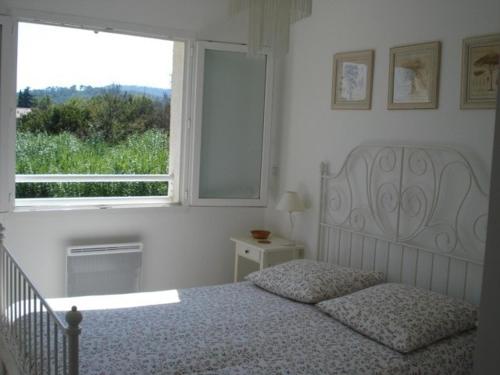 une chambre blanche avec un lit et une fenêtre dans l'établissement Villa tout confort, à 5mn de St Rémy de Provence, à Saint-Étienne-du-Grès