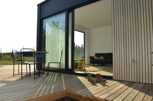 a house with glass doors and chairs on a deck at Land van Engelingen in Helshoven