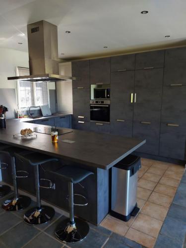 une cuisine avec un grand îlot et des tabourets de bar dans l'établissement Maison agréable pour vacances en Provence, idéale pour 8 personnes, à Entrechaux