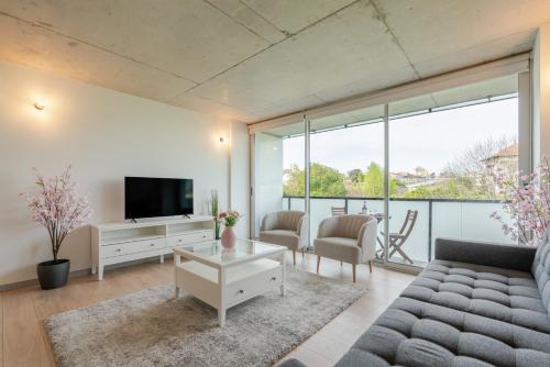 a living room with a couch and a tv at HostWise - Modern Flat w/ Balcony, Garage & Pool in Vila Nova de Gaia