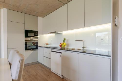 a kitchen with white cabinets and a sink at HostWise - Modern Flat w/ Balcony, Garage & Pool in Vila Nova de Gaia