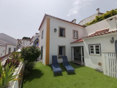 a yard with two blue chairs and a house at Casa da Biquinha in Óbidos