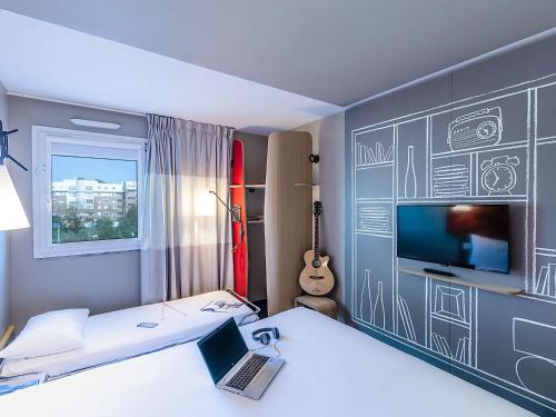 ヴィラ・ノヴァ・デ・ガイアにあるHotel ibis Porto Gaiaのノートパソコンとテレビ付きのベッドが備わる客室です。
