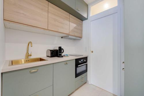 une cuisine avec des armoires blanches et un évier dans l'établissement Peaceful Chic Studio - 2P - Parc Monceau, à Paris