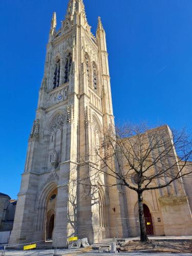 a church with a tall tower with a tree in front at Appart 2 Chambres au coeur de Libourne in Libourne