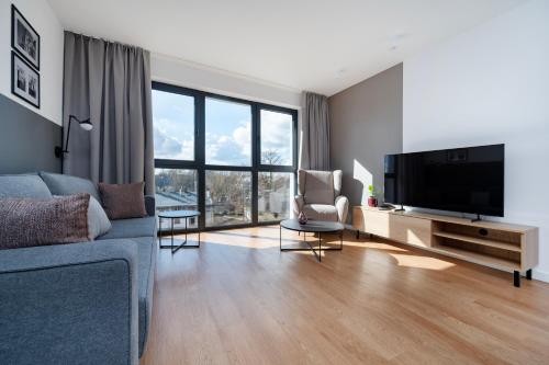 a living room with a blue couch and a flat screen tv at Apartamenty Rocha in Pabianice