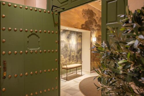 a green door with a chair in a room at Aladro Apartamentos by Valcambre in Jerez de la Frontera