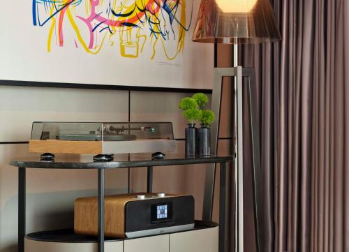 伦敦art'otel London Hoxton, powered by Radisson Hotels的一间带电视和台灯的桌子的房间