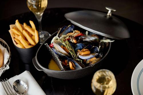 a bowl of mussels and french fries and a glass of wine at art'otel London Hoxton in London