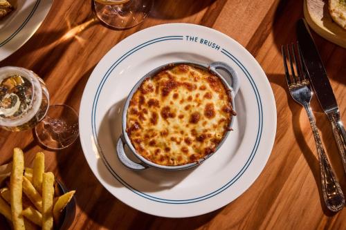 a plate with a casserole on a table with french fries at art'otel London Hoxton in London