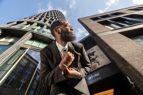 a man in a suit praying in front of a building at art'otel London Hoxton in London