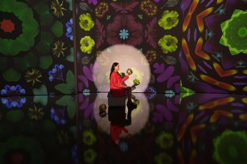 a woman holding a cat in front of a wall with flowers at art'otel London Hoxton in London