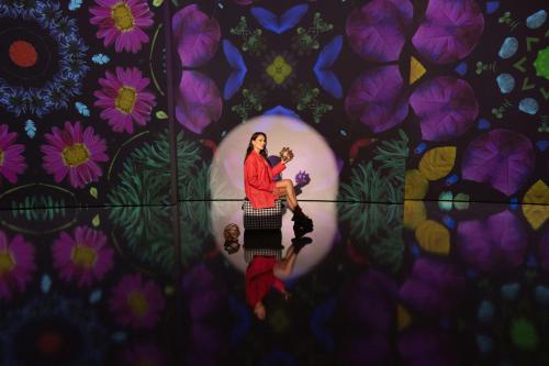 a woman standing in front of a wall with flowers at art'otel London Hoxton in London