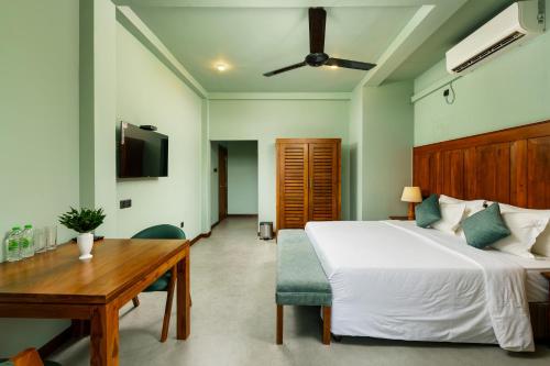 a bedroom with a bed and a wooden table and a desk at Villa Rumassala Luxury Chalets Unawatuna in Unawatuna