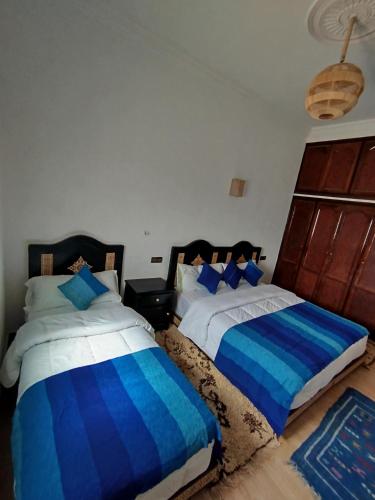two beds in a bedroom with blue and white at Merzouga Lodge in Merzouga