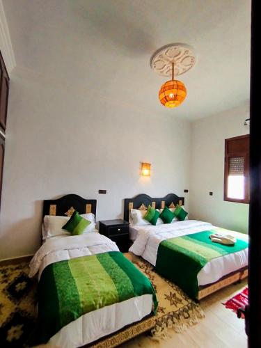 a bedroom with two beds and a chandelier at Merzouga Lodge in Merzouga