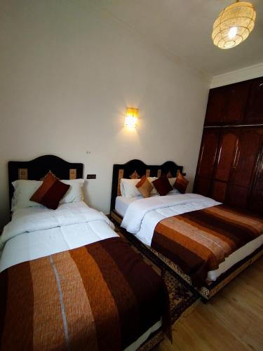 two beds sitting next to each other in a bedroom at Merzouga Lodge in Merzouga
